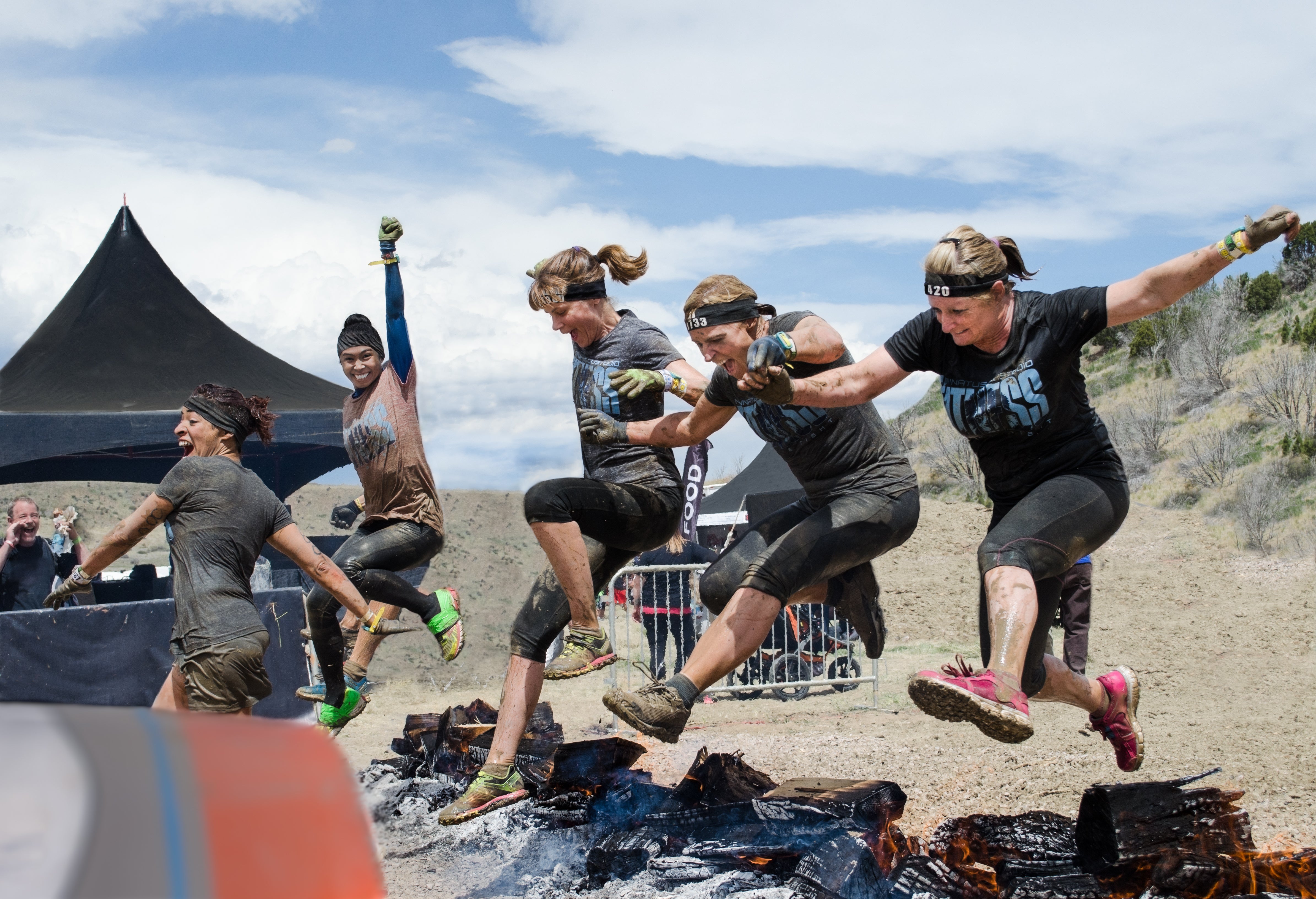 Female Spartan Competitors jumping over hot logs